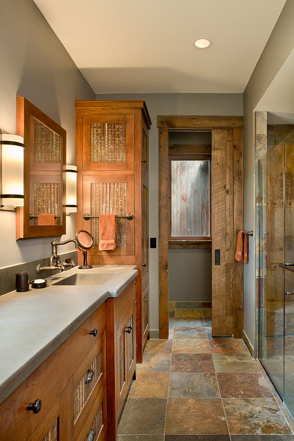 Walk-in shower - mid-sized rustic master slate floor and multicolored floor walk-in shower idea with furniture-like cabinets, an integrated sink, concrete countertops, a hinged shower door and gray countertops