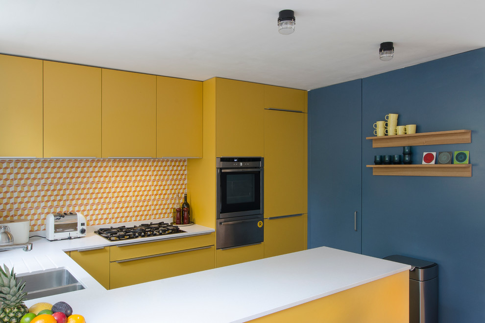 Small contemporary u-shaped open plan kitchen in London with an integrated sink, flat-panel cabinets, yellow cabinets, quartzite benchtops, multi-coloured splashback, cement tile splashback, panelled appliances, dark hardwood floors and a peninsula.
