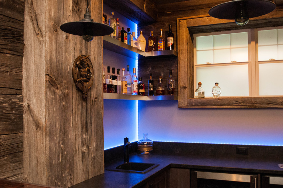 This is an example of a large country u-shaped seated home bar in Other with a drop-in sink, shaker cabinets, light wood cabinets, concrete benchtops, blue splashback, glass sheet splashback, dark hardwood floors and brown floor.