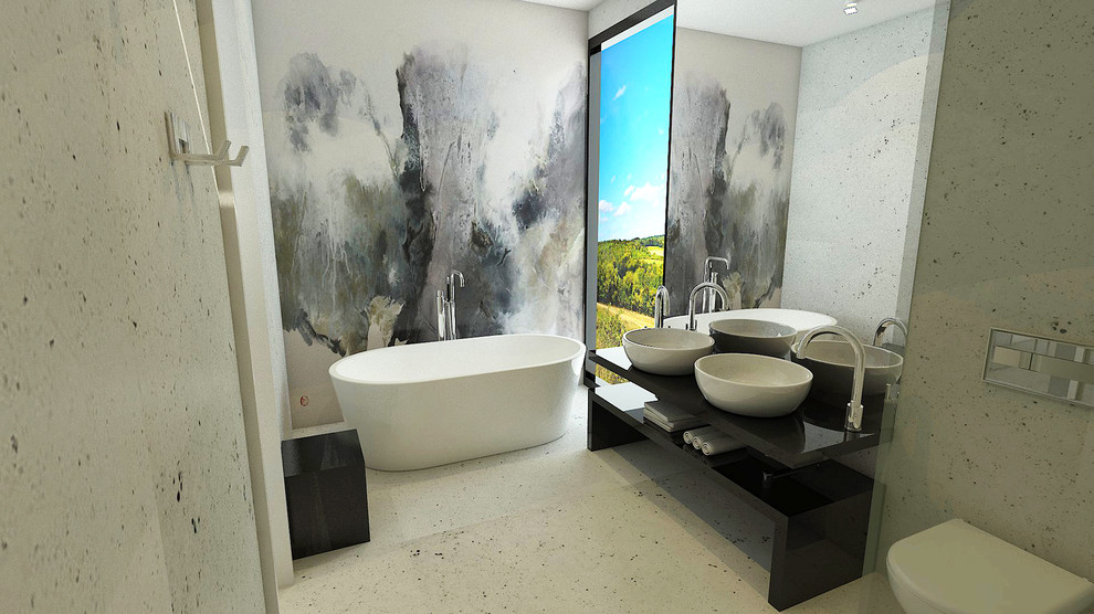Inspiration for a mid-sized contemporary master wet room bathroom in London with grey walls, concrete floors, furniture-like cabinets, black cabinets, a freestanding tub, a wall-mount toilet, gray tile, a vessel sink and marble benchtops.