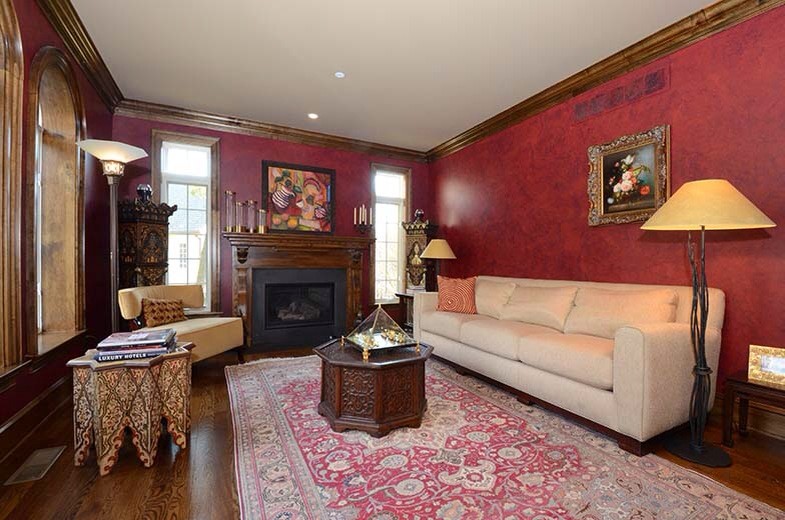 Mid-sized traditional formal enclosed living room in Philadelphia with red walls, medium hardwood floors, a standard fireplace, a wood fireplace surround and no tv.