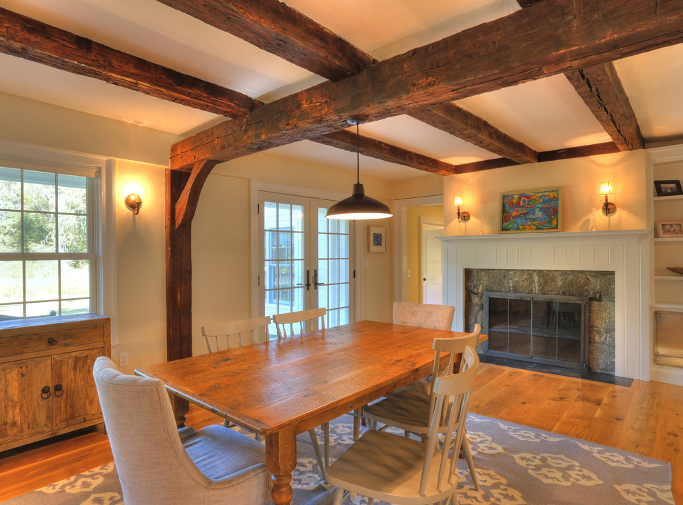 Country dining room in Bridgeport with yellow walls, medium hardwood floors, a standard fireplace and a stone fireplace surround.