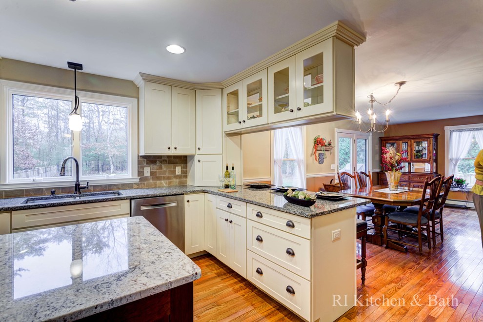 Inspiration for a large transitional u-shaped light wood floor eat-in kitchen remodel in Providence with an undermount sink, shaker cabinets, beige cabinets, granite countertops, brown backsplash, porcelain backsplash, stainless steel appliances and an island