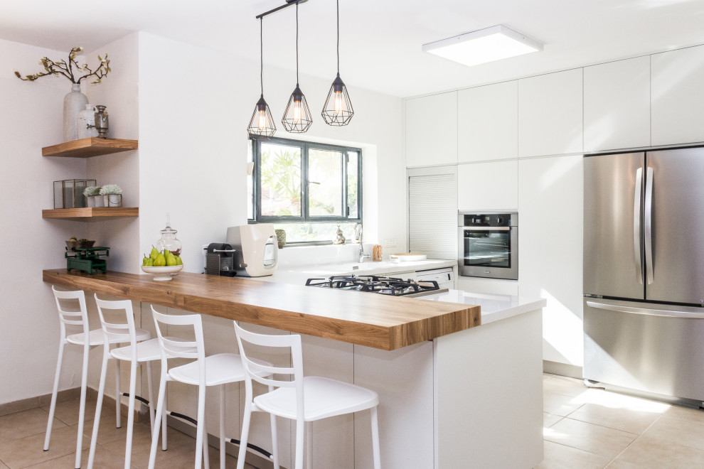 This is an example of a large contemporary u-shaped open plan kitchen in Malaga with an undermount sink, flat-panel cabinets, white cabinets, quartz benchtops, stainless steel appliances, porcelain floors, with island, beige floor, white benchtop and white splashback.
