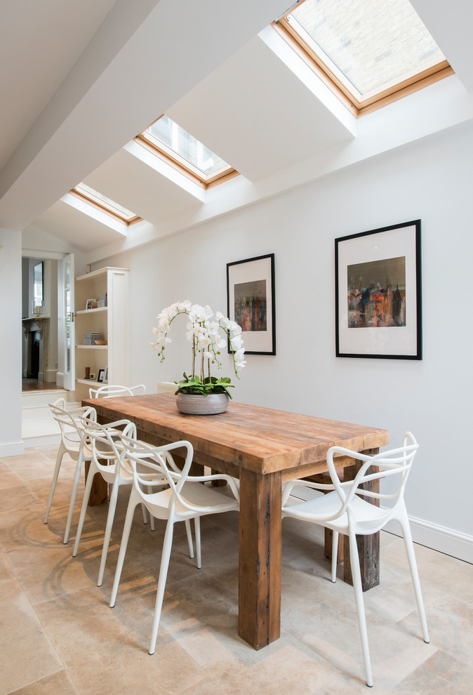 Mid-sized contemporary dining room in London with white walls and beige floor.