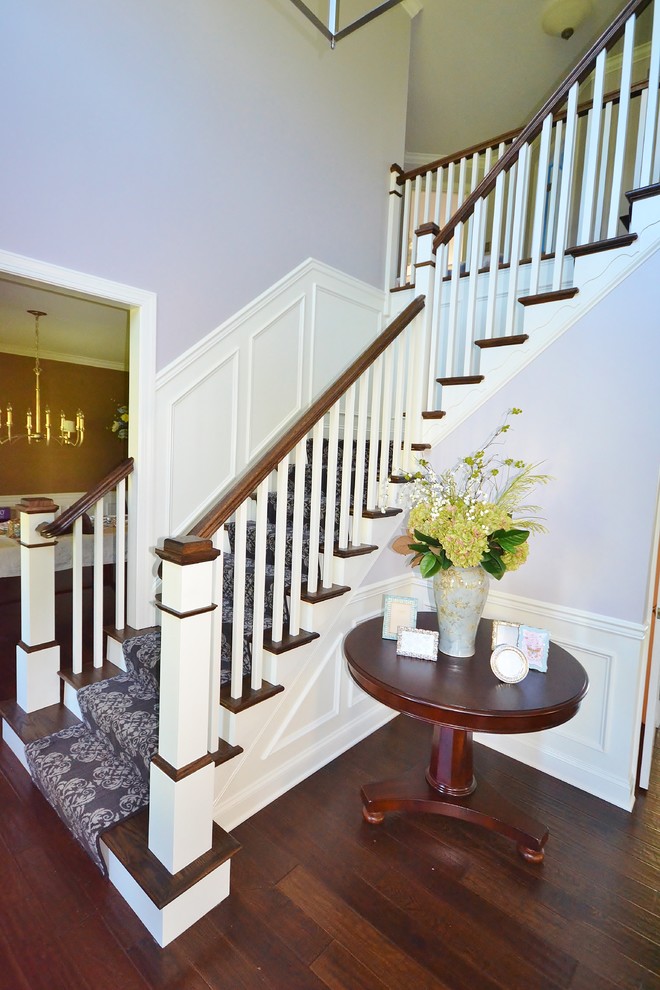 Large transitional wood l-shaped staircase in Philadelphia with carpet risers and wood railing.