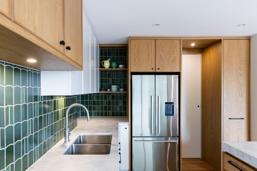 This is an example of a large contemporary l-shaped open plan kitchen in Melbourne with a submerged sink, recessed-panel cabinets, medium wood cabinets, granite worktops, green splashback, ceramic splashback, black appliances, medium hardwood flooring, an island and grey worktops.