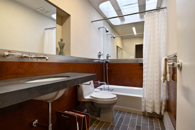 Design ideas for a mid-sized midcentury 3/4 bathroom in New York with an alcove tub, a shower/bathtub combo, a two-piece toilet, beige walls, vinyl floors, an undermount sink, solid surface benchtops, brown floor, brown benchtops and a shower curtain.