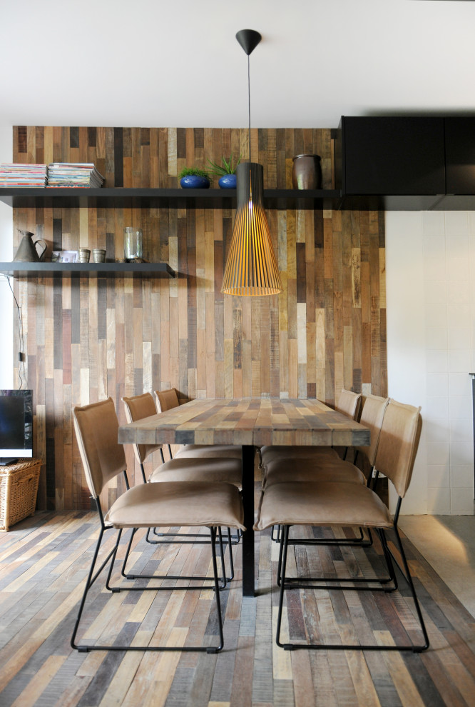 This is an example of a contemporary kitchen/dining combo with brown floor and wood walls.