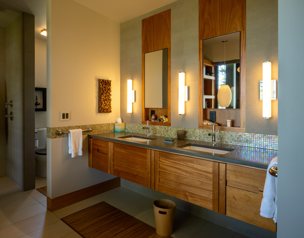 Стильный дизайн: большая главная ванная комната в стиле модернизм с плоскими фасадами, светлыми деревянными фасадами, японской ванной, душевой комнатой, зеленой плиткой, стеклянной плиткой, бежевыми стенами, полом из керамогранита, врезной раковиной, стеклянной столешницей, бежевым полом, открытым душем, черной столешницей, тумбой под две раковины и подвесной тумбой - последний тренд