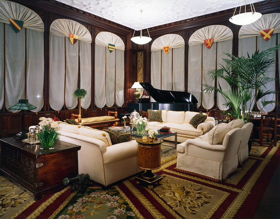 This is an example of an expansive traditional enclosed living room in New York with brown walls and dark hardwood floors.