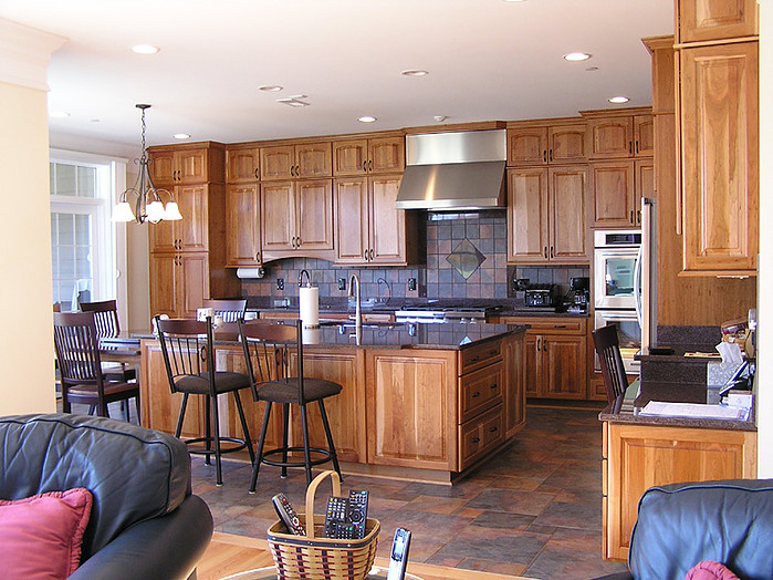 Mountain style l-shaped ceramic tile kitchen photo in DC Metro with an undermount sink, raised-panel cabinets, medium tone wood cabinets, granite countertops, multicolored backsplash, ceramic backsplash, stainless steel appliances and an island
