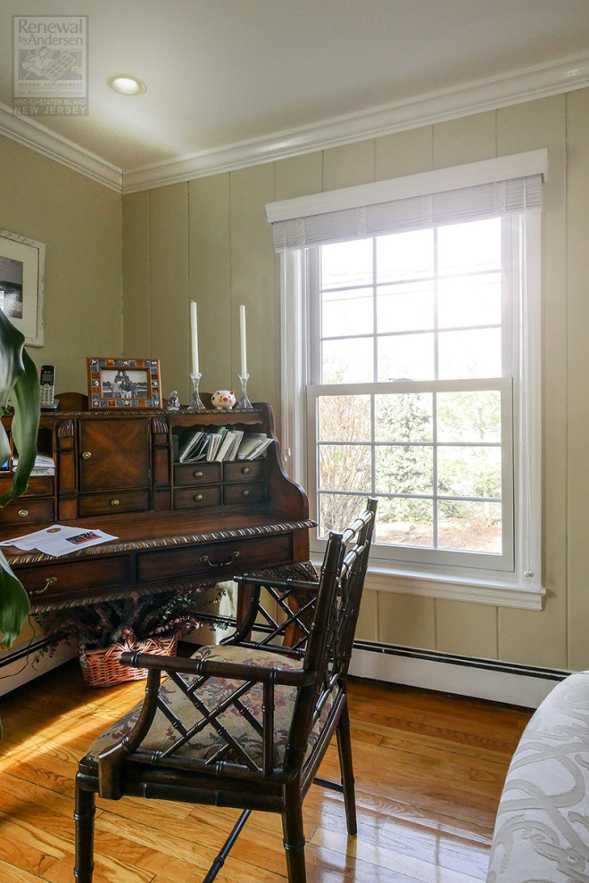 Photo of a small home office in New York with green walls, medium hardwood floors, no fireplace, a freestanding desk, brown floor and panelled walls.