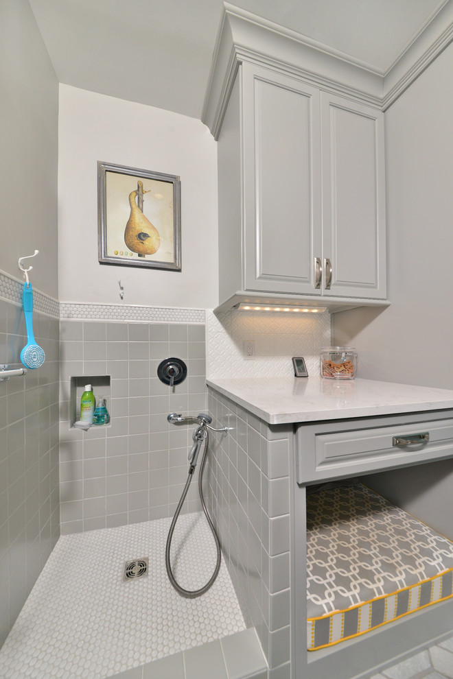 Mid-sized traditional single-wall utility room in Cleveland with an utility sink, raised-panel cabinets, grey cabinets, quartz benchtops, grey walls, porcelain floors and a stacked washer and dryer.