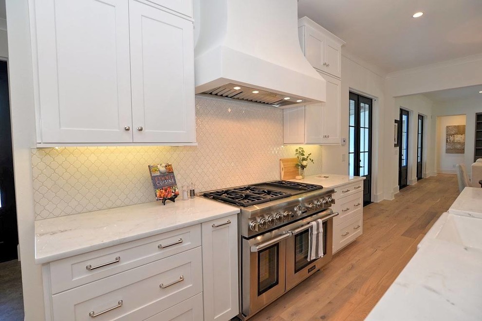 Kitchen - transitional kitchen idea in Orlando with recessed-panel cabinets, white cabinets, white backsplash, ceramic backsplash and an island