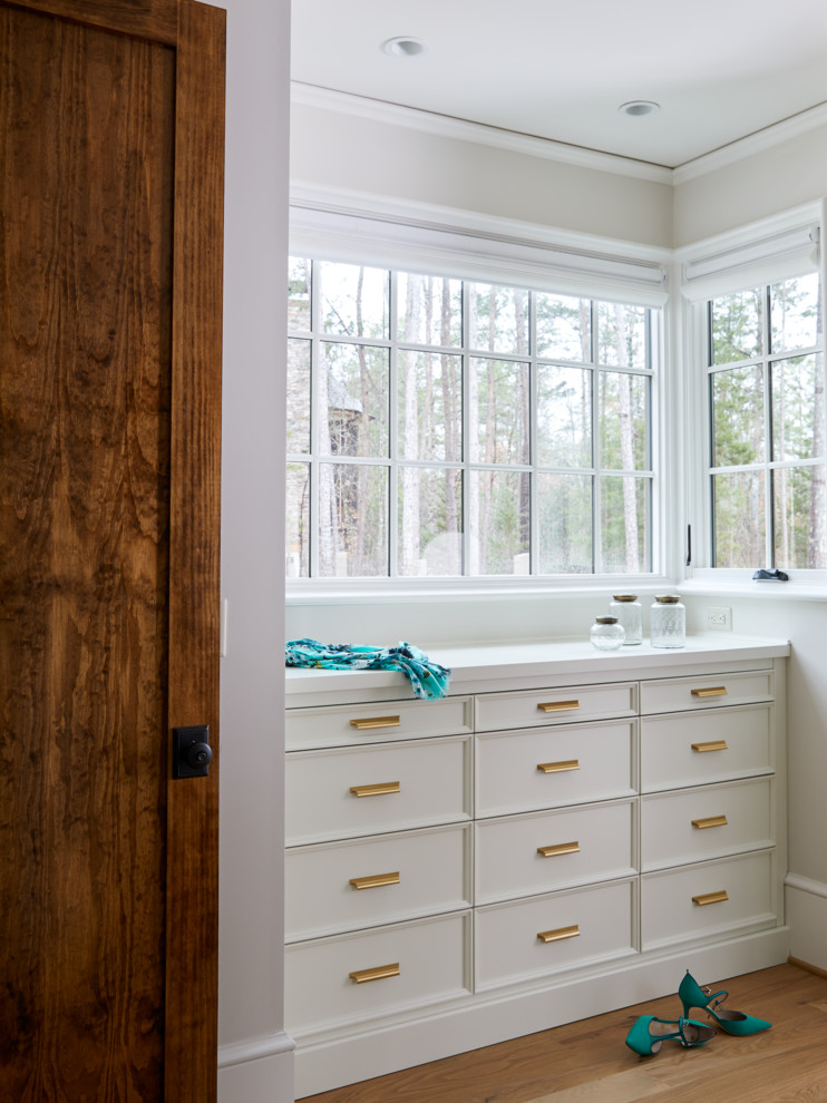 Photo of a country bathroom in Charlotte with furniture-like cabinets, white cabinets, light hardwood floors and wood benchtops.