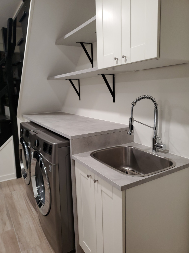 Inspiration for a contemporary single-wall utility room in DC Metro with a single-bowl sink, shaker cabinets, grey cabinets, concrete benchtops, white walls, laminate floors, a side-by-side washer and dryer, grey floor and grey benchtop.