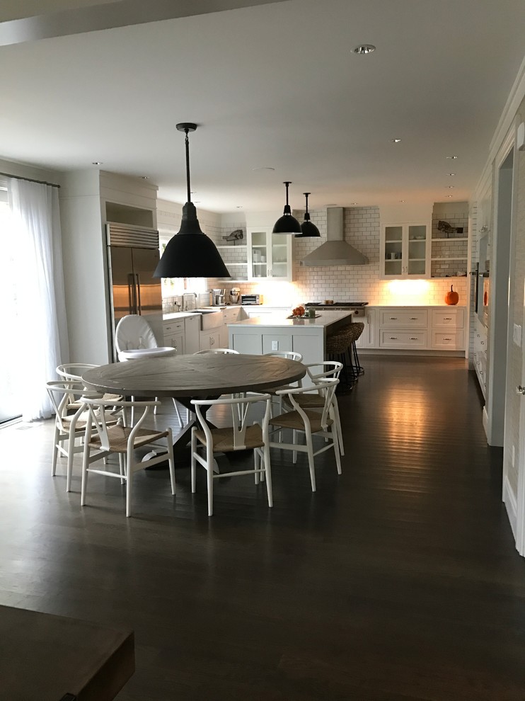 Example of a huge u-shaped dark wood floor open concept kitchen design in Bridgeport with a farmhouse sink, beaded inset cabinets, white cabinets, marble countertops, white backsplash, subway tile backsplash, stainless steel appliances and an island
