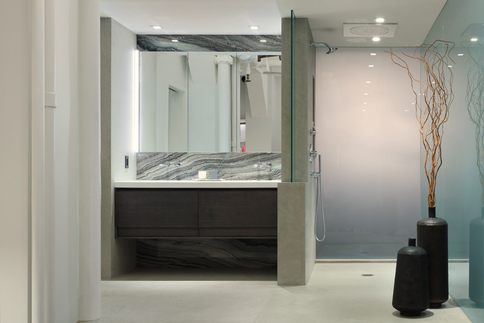This is an example of a mid-sized modern master bathroom in New York with flat-panel cabinets, dark wood cabinets, an open shower, gray tile, glass sheet wall, white walls, an open shower, an undermount sink, concrete floors, engineered quartz benchtops, grey floor and white benchtops.