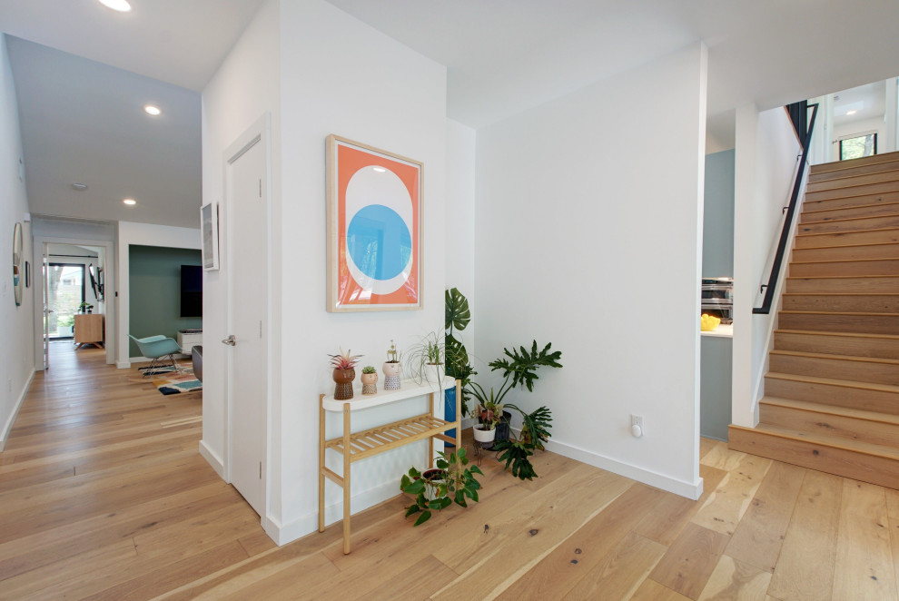Design ideas for a large scandinavian foyer in Austin with white walls, light hardwood floors, a single front door, a yellow front door and brown floor.