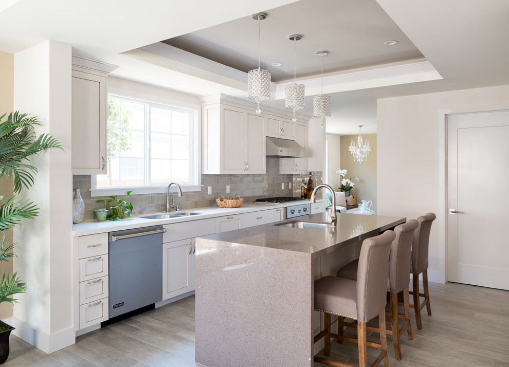 Design ideas for a transitional galley kitchen in Los Angeles with an undermount sink, shaker cabinets, white cabinets, grey splashback, subway tile splashback, stainless steel appliances, dark hardwood floors and with island.