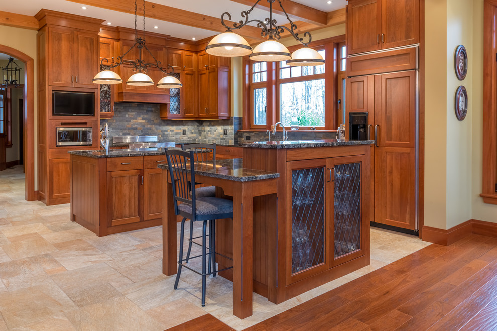 This is an example of a large transitional l-shaped open plan kitchen in Ottawa with multi-coloured splashback, panelled appliances, multiple islands, shaker cabinets, medium wood cabinets, granite benchtops, stone tile splashback, porcelain floors and a farmhouse sink.