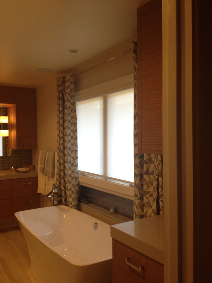 Mid-sized transitional master blue tile and subway tile light wood floor and blue floor freestanding bathtub photo with flat-panel cabinets, distressed cabinets, beige walls, an undermount sink, solid surface countertops and a hinged shower door
