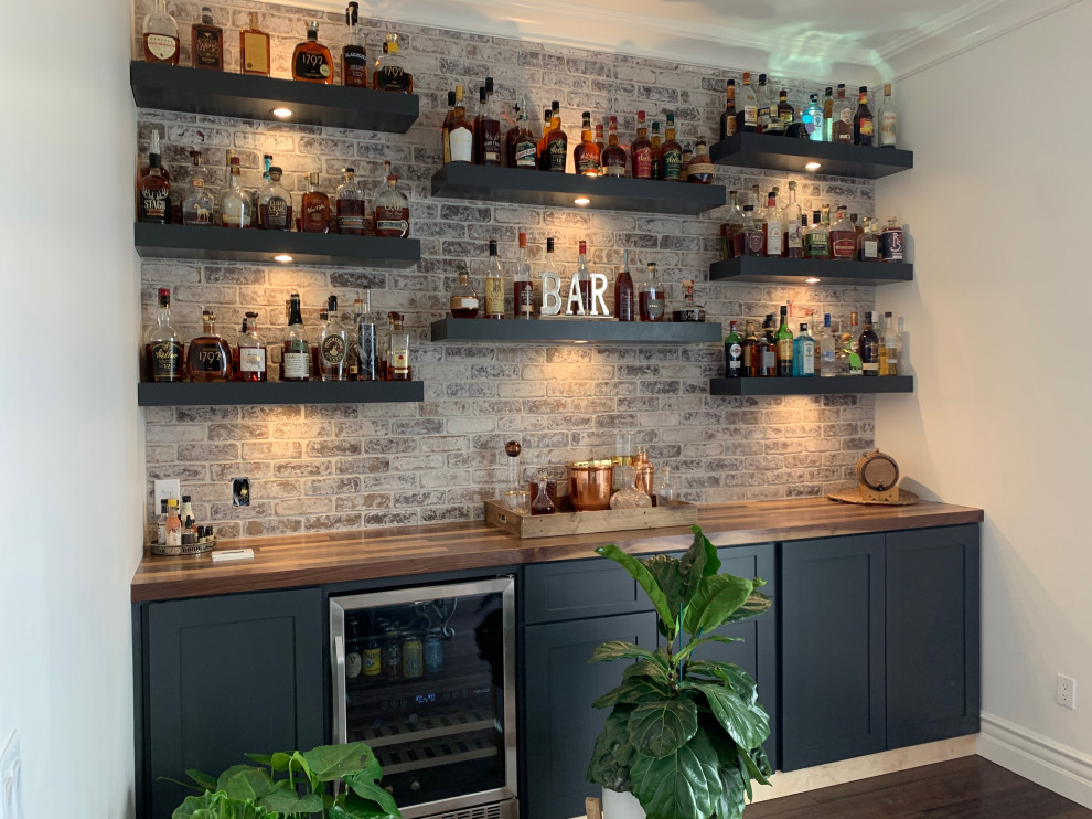 Design ideas for a small traditional single-wall home bar in Phoenix with flat-panel cabinets, wood benchtops, brick splashback and medium hardwood floors.