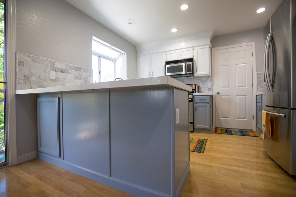 Photo of a modern l-shaped kitchen in Sacramento with an undermount sink, white cabinets, quartz benchtops, blue splashback, marble splashback, stainless steel appliances and a peninsula.