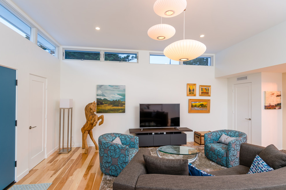 Photo of a mid-sized midcentury open concept family room in Orange County with white walls, medium hardwood floors, no fireplace and a freestanding tv.