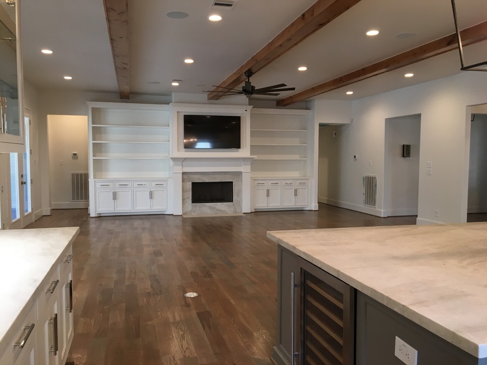 Photo of a large transitional open concept living room in Houston with white walls, medium hardwood floors, a standard fireplace, a stone fireplace surround, a built-in media wall and grey floor.