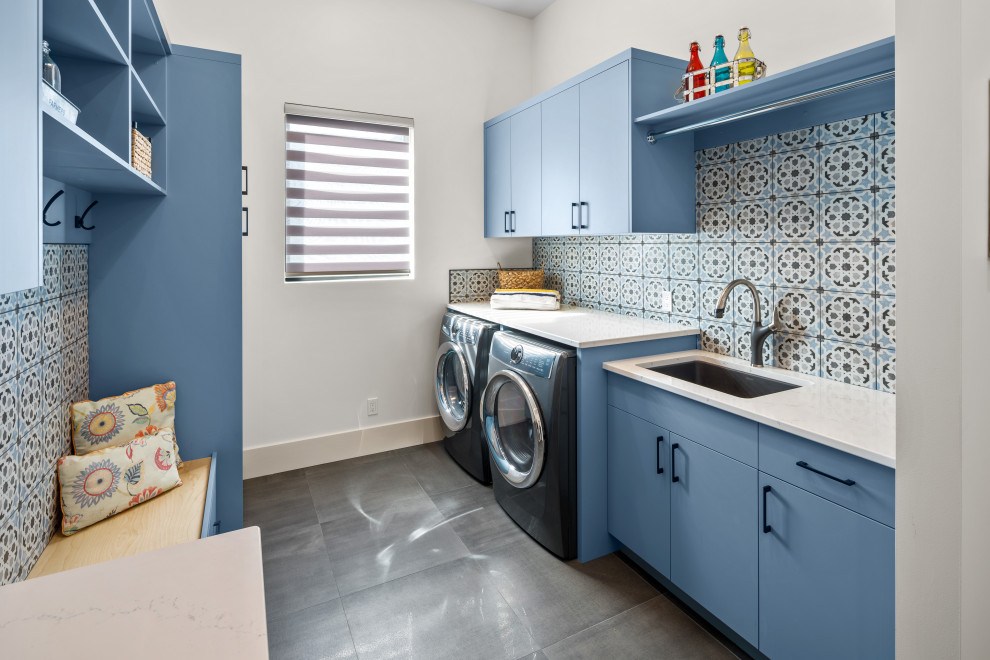 This is an example of a contemporary galley utility room in Vancouver with an undermount sink, flat-panel cabinets, blue cabinets, quartz benchtops, blue splashback, ceramic splashback, white walls, ceramic floors, a side-by-side washer and dryer, grey floor and yellow benchtop.