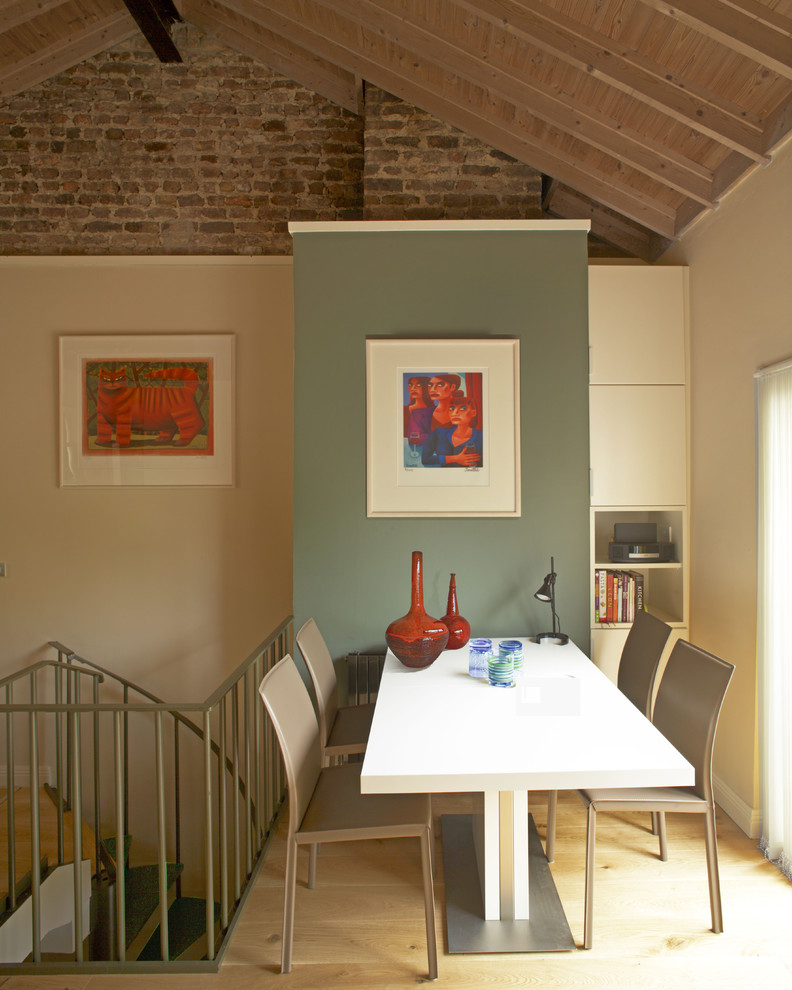 This is an example of a modern open plan dining in Dublin with multi-coloured walls and light hardwood floors.