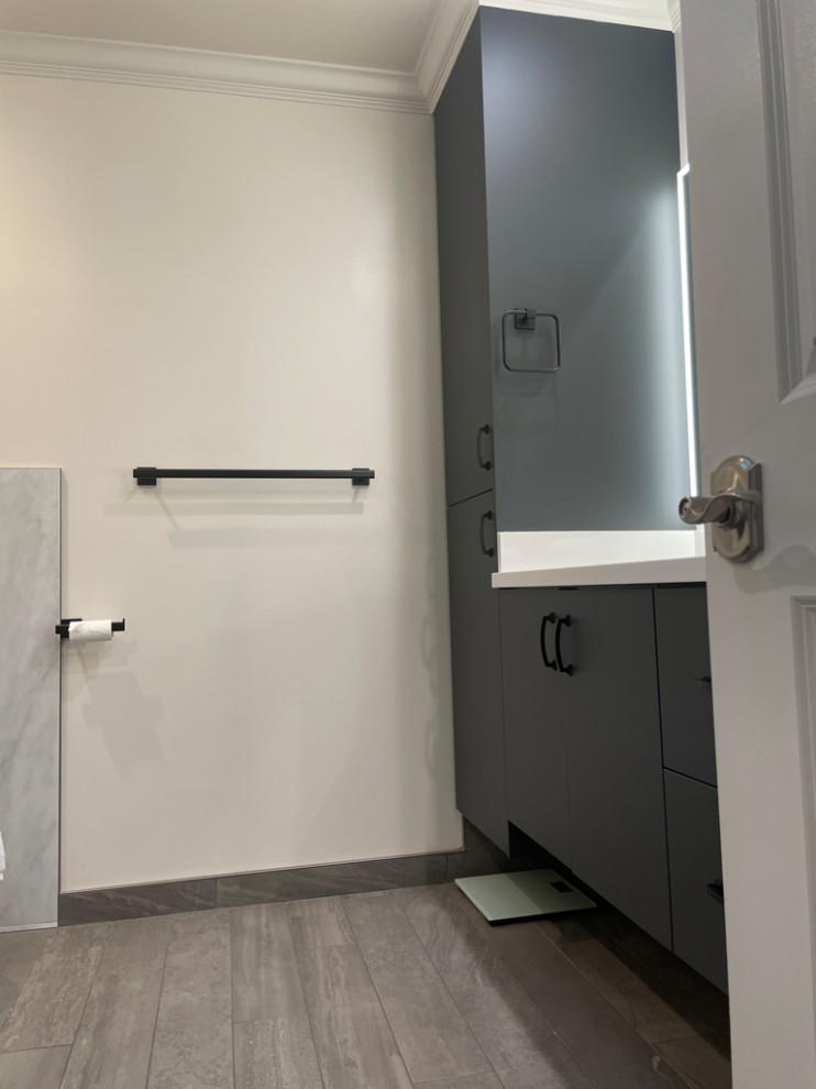 Photo of a medium sized contemporary ensuite bathroom in San Francisco with flat-panel cabinets, grey cabinets, a corner shower, a one-piece toilet, grey tiles, porcelain tiles, white walls, ceramic flooring, a built-in sink, granite worktops, grey floors, a hinged door, white worktops, double sinks and a built in vanity unit.