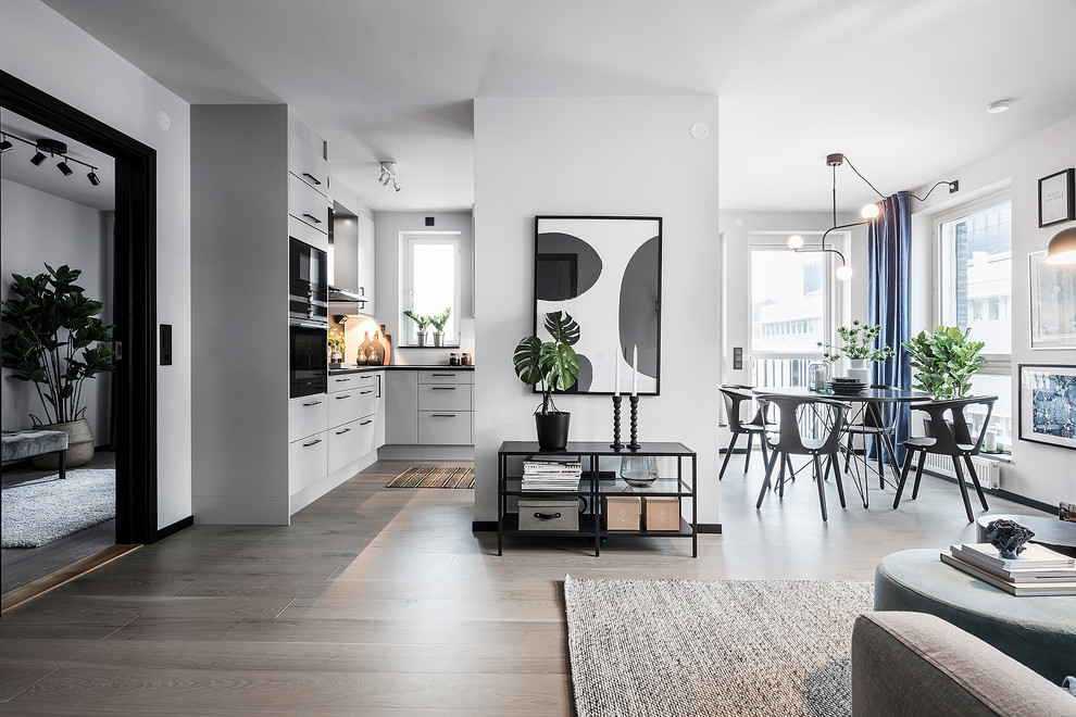 This is an example of a large scandinavian open concept living room in Gothenburg with white walls, light hardwood floors, no fireplace, no tv and grey floor.