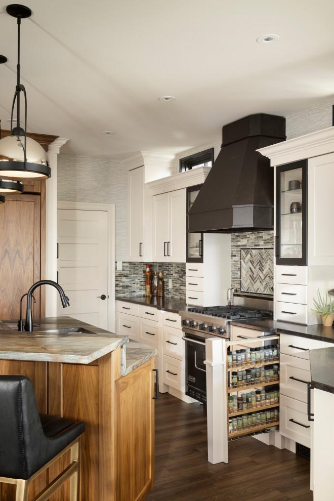 Idéer för att renovera ett stort vintage svart svart l-kök, med en dubbel diskho, luckor med infälld panel, vita skåp, granitbänkskiva, grått stänkskydd, stänkskydd i glaskakel, svarta vitvaror, mellanmörkt trägolv, en köksö och brunt golv