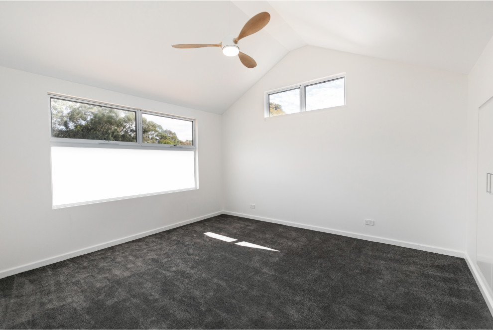 アデレードにある中くらいなミッドセンチュリースタイルのおしゃれなロフト寝室 (白い壁、カーペット敷き、グレーの床、三角天井) のインテリア