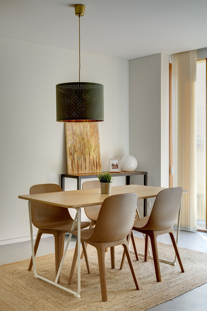 Modelo de comedor contemporáneo pequeño abierto con paredes blancas, suelo de cemento y suelo gris