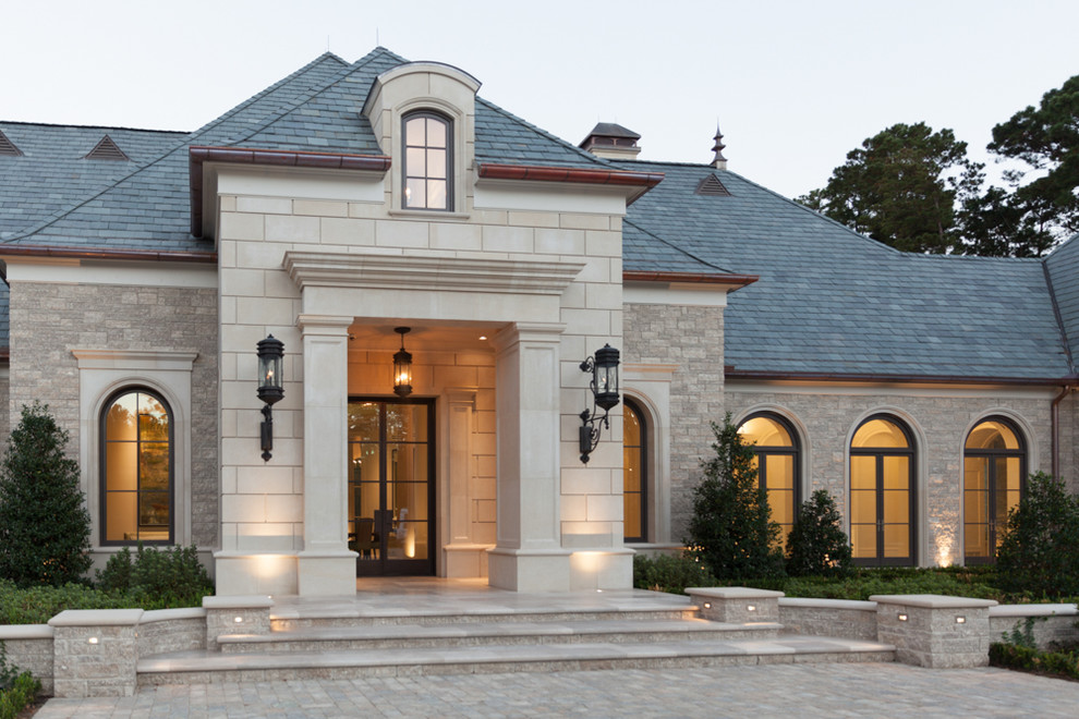Inspiration for an expansive mediterranean beige exterior in Houston with stone veneer and a gable roof.