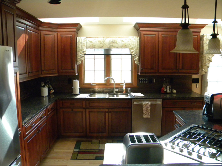 Eat-in kitchen - mid-sized transitional u-shaped light wood floor eat-in kitchen idea with an undermount sink, raised-panel cabinets, medium tone wood cabinets, granite countertops, multicolored backsplash, stone tile backsplash, stainless steel appliances and an island