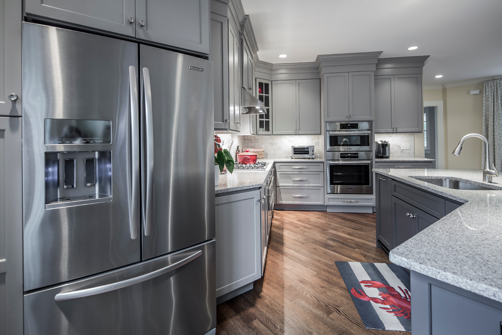 Design ideas for a large transitional single-wall eat-in kitchen in Boston with an undermount sink, flat-panel cabinets, grey cabinets, granite benchtops, white splashback, ceramic splashback, stainless steel appliances, dark hardwood floors and with island.