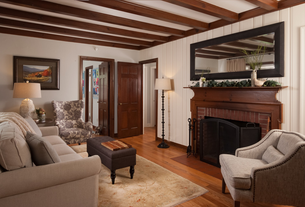 Photo of a small country enclosed family room in Other with beige walls, medium hardwood floors, a standard fireplace, a brick fireplace surround and brown floor.