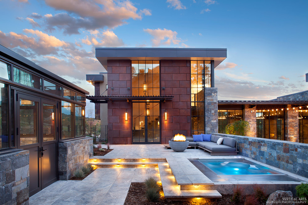 This is an example of a large contemporary courtyard patio in Denver with a fire feature, tile and a pergola.