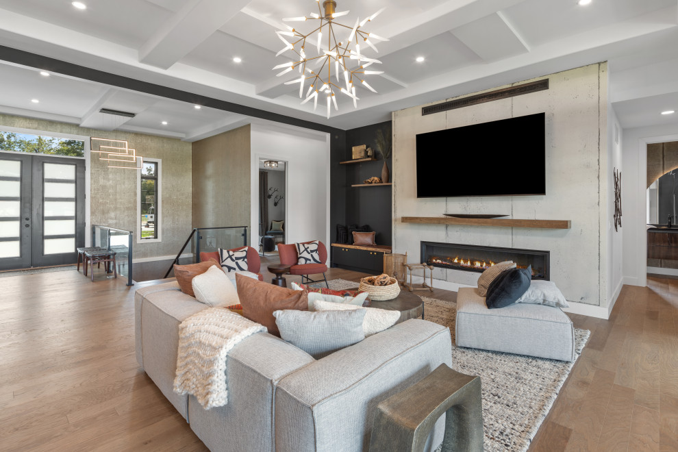 This is an example of a large contemporary living room in Cincinnati with a concrete fireplace surround, a wall mounted tv and a coffered ceiling.