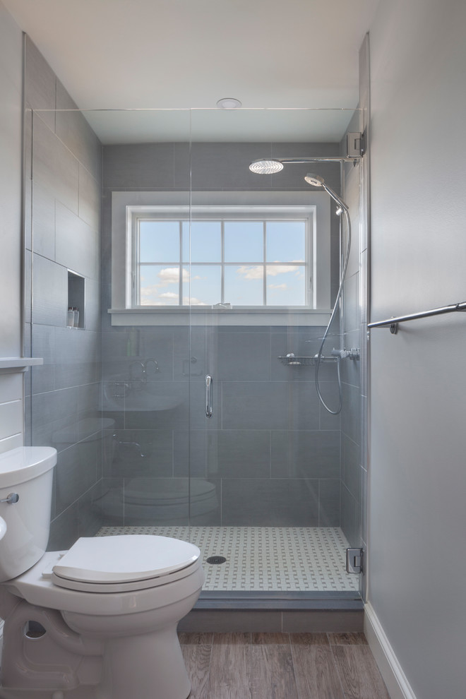 Photo of a mid-sized transitional 3/4 bathroom in Other with an alcove shower, a two-piece toilet, gray tile, porcelain tile, grey walls, dark hardwood floors, brown floor and a hinged shower door.