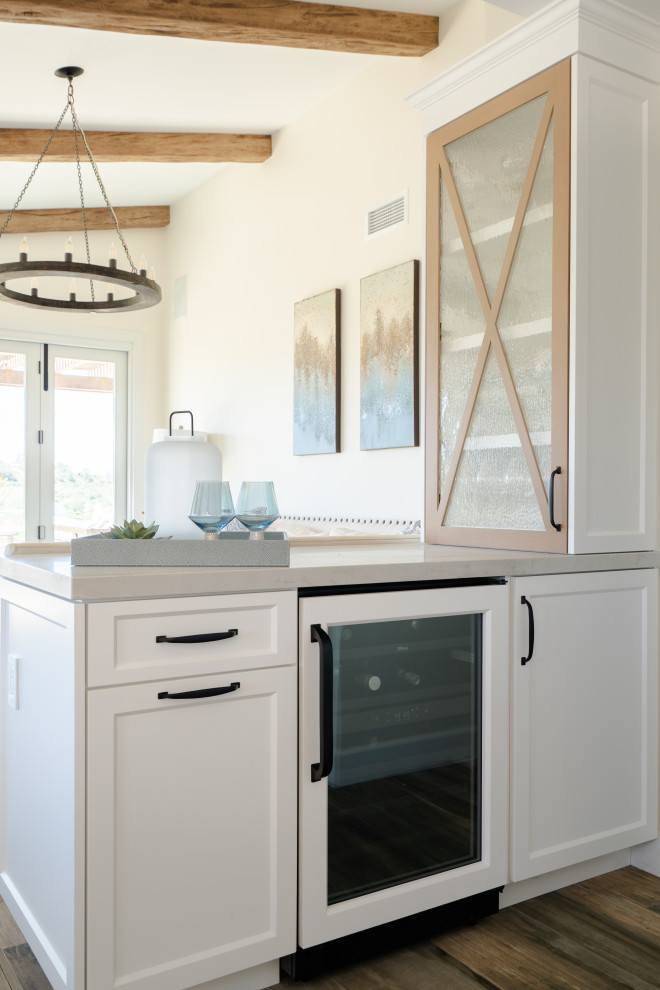 Inspiration for an expansive farmhouse galley open plan kitchen in San Diego with a belfast sink, recessed-panel cabinets, light wood cabinets, quartz worktops, beige splashback, ceramic splashback, stainless steel appliances, porcelain flooring, an island, brown floors, white worktops and exposed beams.