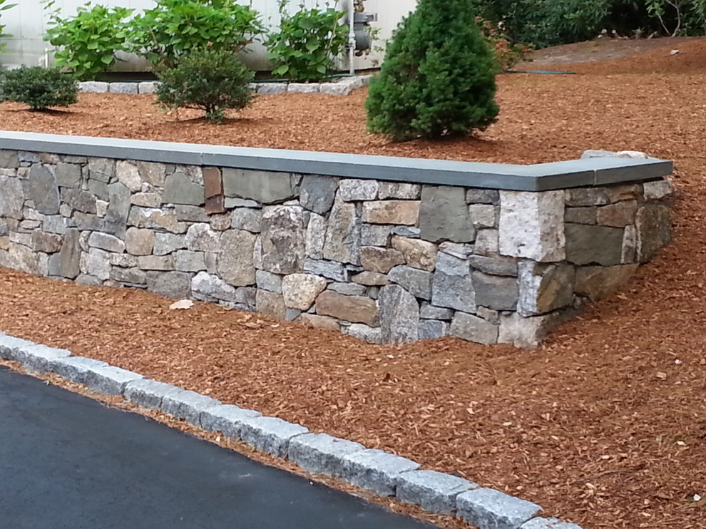 Inspiration for a mid-sized traditional front yard partial sun garden in Boston with a retaining wall and mulch.