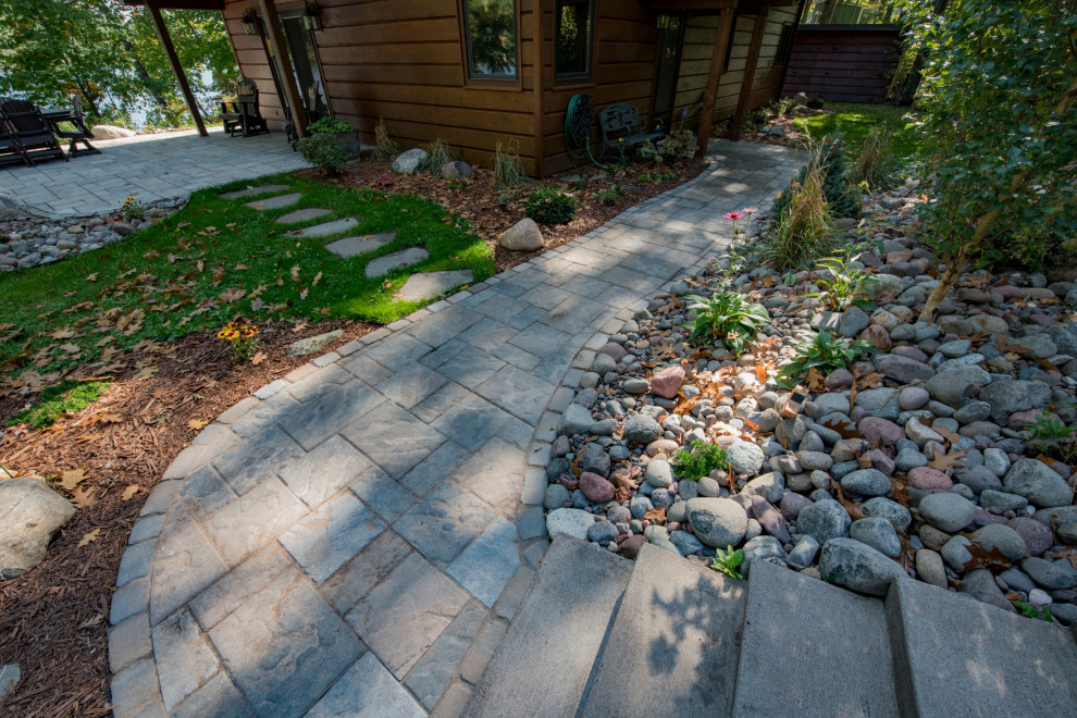 Photo of a mid-sized rustic partial sun backyard concrete paver walkway.
