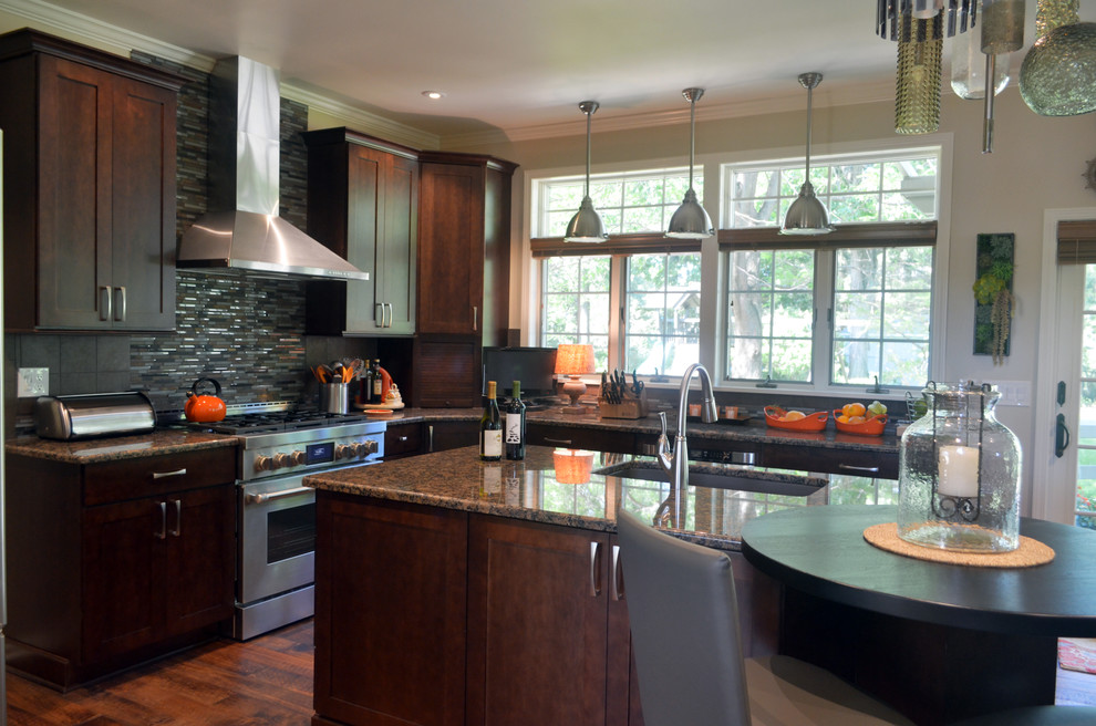 Example of a large transitional u-shaped medium tone wood floor kitchen design with an undermount sink, shaker cabinets, brown cabinets, granite countertops, stainless steel appliances and an island