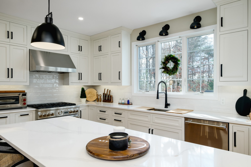 This is an example of a large classic u-shaped kitchen/diner in Boston with a submerged sink, recessed-panel cabinets, white cabinets, engineered stone countertops, white splashback, ceramic splashback, stainless steel appliances, light hardwood flooring, an island and white worktops.